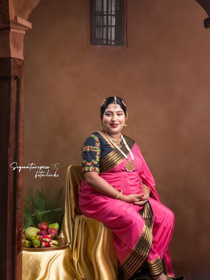 A seated portrait inspired by royalty, with a beautiful pink saree and traditional props like a fruit platter.