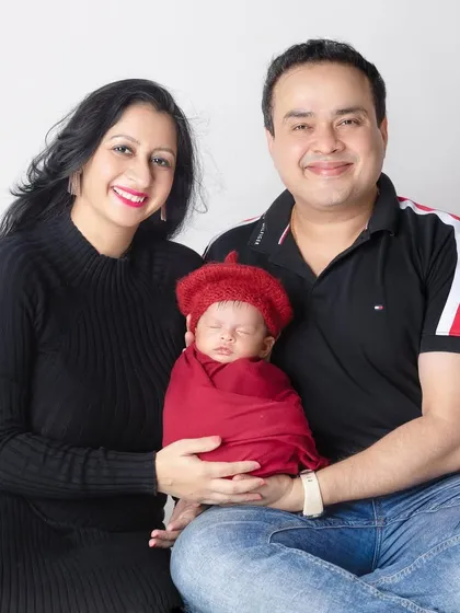 A cozy family portrait, sitting together on the floor. The baby's little red hat adds a pop of color and cuteness.
