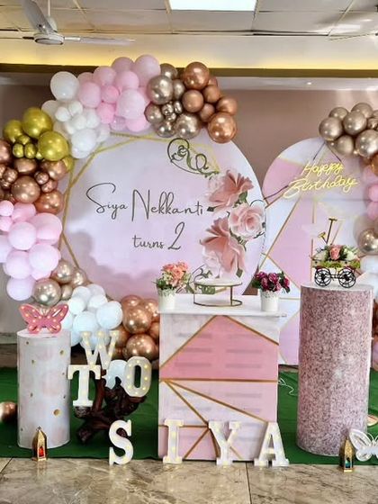 A sophisticated butterfly-themed 2nd birthday party. The design uses a modern color palette of pink, rose gold, and white, with geometric-patterned backdrops.