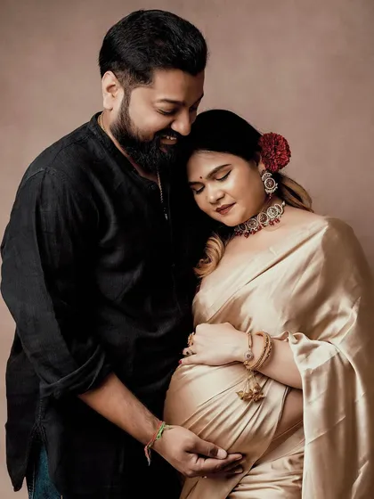 The elegance of tradition meets the beauty of motherhood. This studio maternity portrait, with the couple in classic attire, highlights the deep, quiet love and anticipation of their journey.
