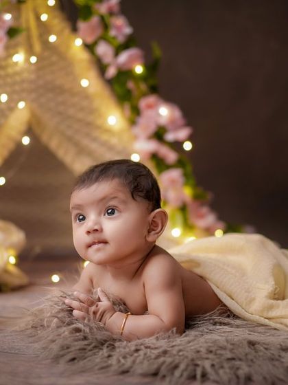 A curious little explorer. This milestone session captures a baby's tummy time in a beautifully lit, boho-themed setup with a teepee and flowers.