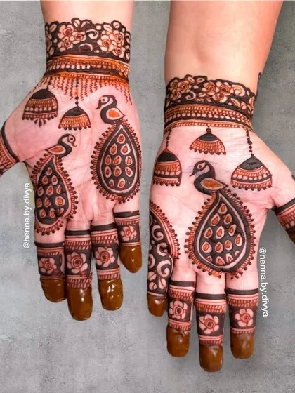 I love creating peacock mehendi. This design showcases twin peacocks on each palm, surrounded by hanging jhumkas, creating a symmetrical and festive look.