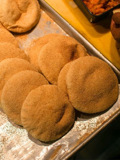 A tray of freshly baked poee, the star of our one-day-only sandwich shop. This whole wheat bread, crusty on the outside and soft inside, is perfect for soaking up flavors.