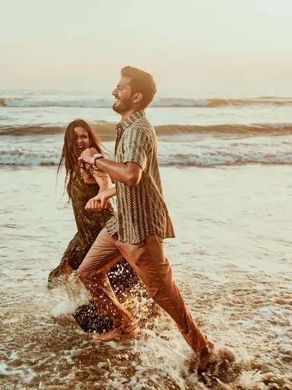A couple runs through the waves at a Goan beach, splashing and laughing. This action shot is full of energy and perfectly captures the feeling of a carefree beach romance.
