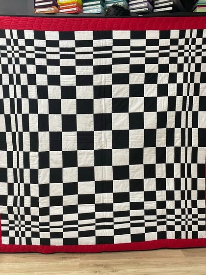 A bold, graphic quilt with a black-and-white checkerboard design that creates an optical illusion.