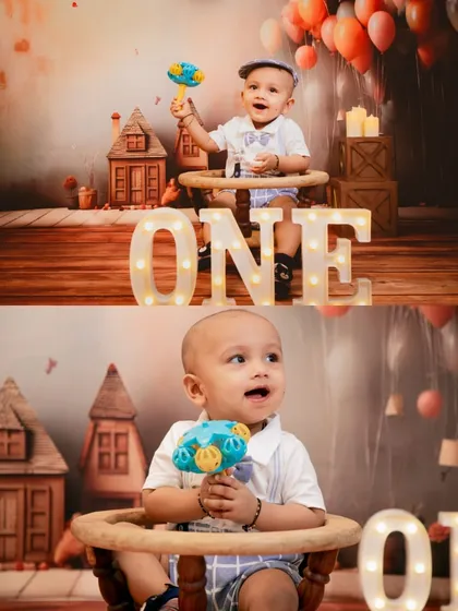 A studio milestone shoot featuring a baby boy with light-up 'ONE' letters and a charming, rustic house-themed backdrop.