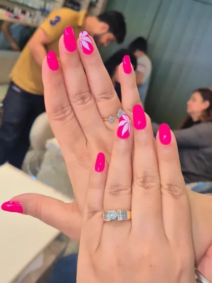 A vibrant and cheerful look featuring a bright, hot pink gel polish on rounded nails. To add a special touch, I hand-painted a simple yet elegant white floral design on the accent nails. This is a perfect example of a stylish yet wearable everyday design.