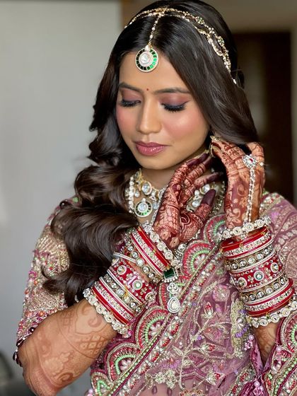 A detailed shot of the bride's hands and makeup. The soft glam look is the perfect complement to her intricate henna and beautiful jewelry.