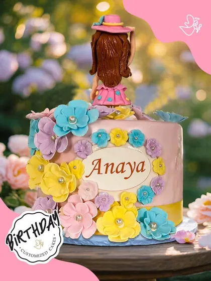 A vibrant floral cake for Anaya's birthday, featuring a wreath of colorful sugar flowers and a cute figurine topper. It's as beautiful and cheerful as a summer garden.