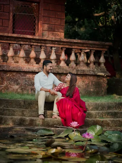 The couple sits on the steps of a temple pond, surrounded by blooming water lilies. This beautifully composed shot is full of romance and natural beauty.