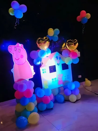 A fun Peppa Pig house cutout prop with balloon decorations, perfect for photos.
