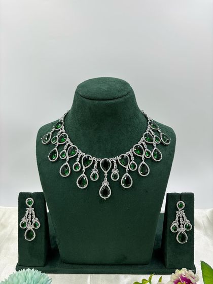 A contemporary silver-plated necklace set with teardrop-shaped stones. This design is available in emerald green, pink, red, and dark blue, offering a sleek and modern look for any occasion.