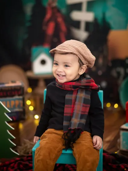 A bright, happy smile from our little woodsman. The warm fairy lights in the background add a magical touch to the camping theme.