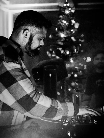 A black and white photo of me in a flannel shirt, focused on the mix, with a Christmas tree in the background, showing a more festive, intimate gig.