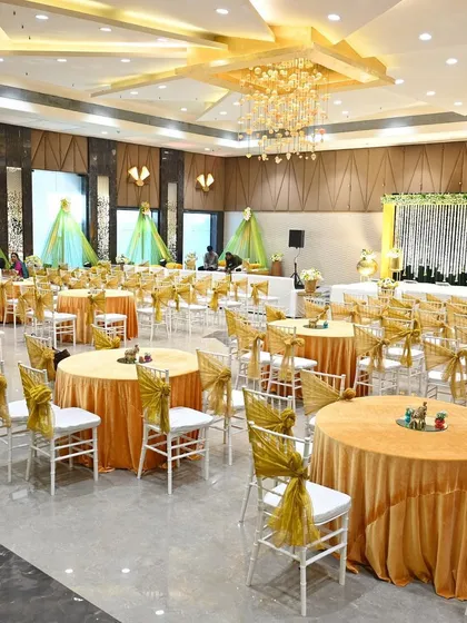 The complete Mehendi event space, with yellow-themed round table guest seating and individual seating areas draped in green and gold.