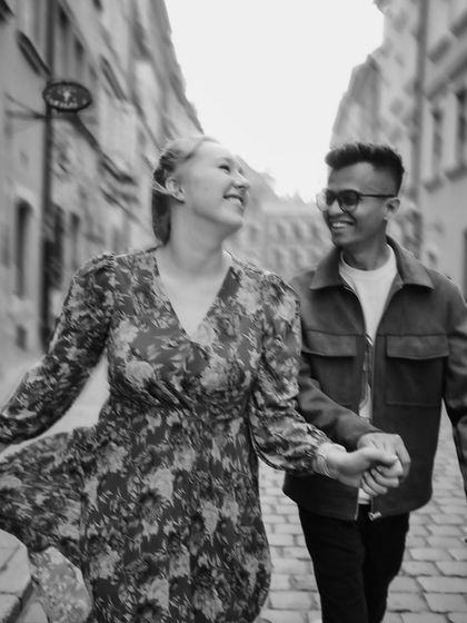 A black and white photo capturing the dynamic movement and joy of the couple walking hand-in-hand.