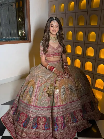 A full-length portrait of this gorgeous bride. The makeup is perfectly balanced with her intricate, colorful lehenga, featuring soft waves in her hair and a radiant complexion.