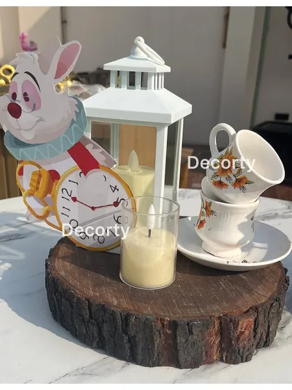 A charming table centerpiece featuring the White Rabbit, a lantern, and stacked teacups, perfectly capturing the essence of Wonderland.