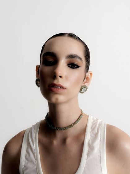 A direct and powerful portrait that gives a clear view of the intricate choker and earring set. The model's intense gaze adds to the strength of the image.