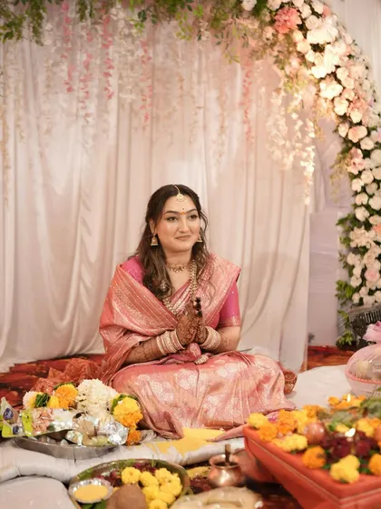 The bride-to-be is seated during her engagement pooja, looking serene and beautiful.