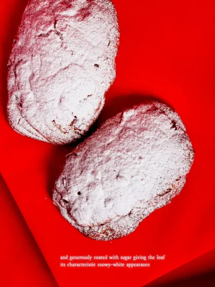 The loaf is then generously coated in icing sugar, giving it a characteristic snowy-white appearance that symbolizes the holiday season.