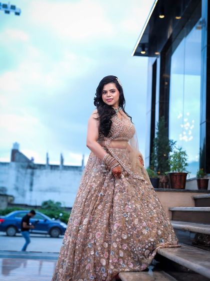 A full-length portrait of a woman on a staircase, showcasing her embroidered lehenga against an urban backdrop.