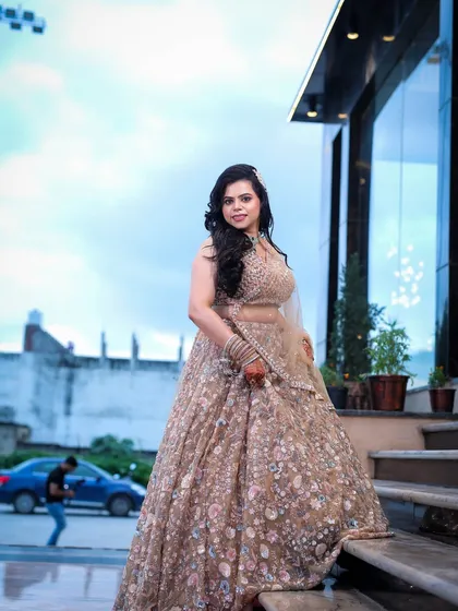 A full-length portrait of a woman on a staircase, showcasing her embroidered lehenga against an urban backdrop.