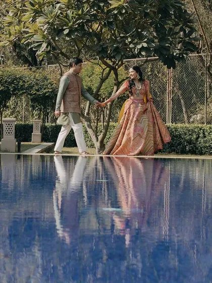 A beautiful reflection shot by the pool. This creative composition adds an artistic touch, capturing the couple's serene walk and the stunning symmetry of the location.