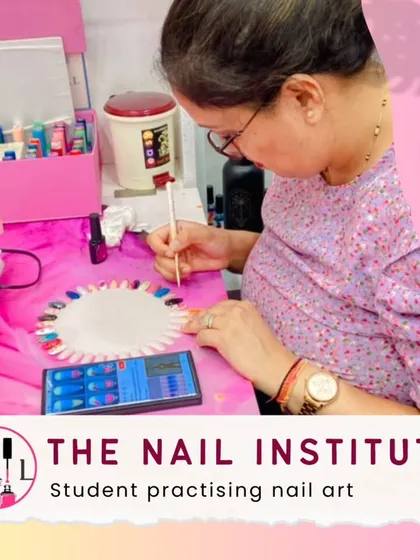 With a reference photo on her phone, this student practices recreating a specific nail art design on a practice wheel.