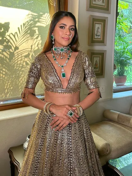The full look, showcasing the stunning black and gold lehenga. The makeup is designed to be dramatic and unforgettable, perfect for a grand event.