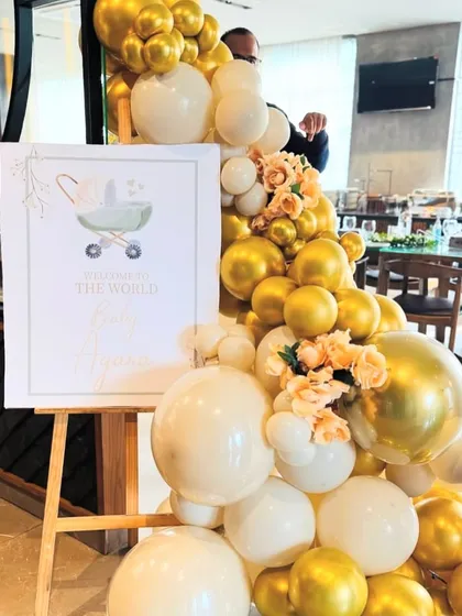 A personalized 'Welcome to the World' sign for Baby Ayana, framed by a beautiful gold and white balloon arrangement.
