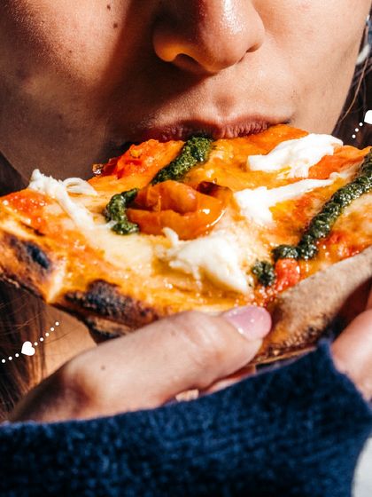 A perfect bite of our pesto and tomato pizza. The fresh pesto, sweet tomatoes, and creamy mozzarella come together beautifully.