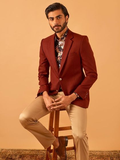 A seated portrait in the maroon blazer, conveying a sense of relaxed confidence and style.