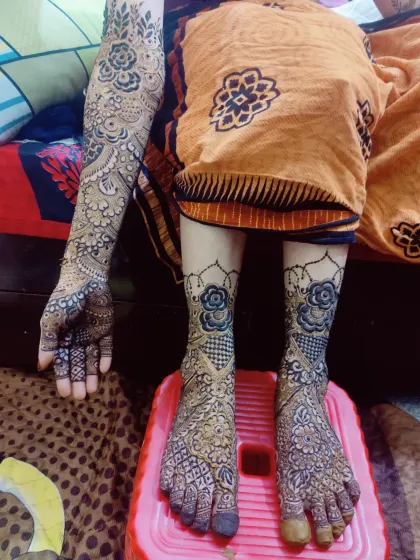 This full bridal package showcases a beautiful contrast between dense patterns on the feet and more spaced-out floral designs on the arms, all done with organic henna.