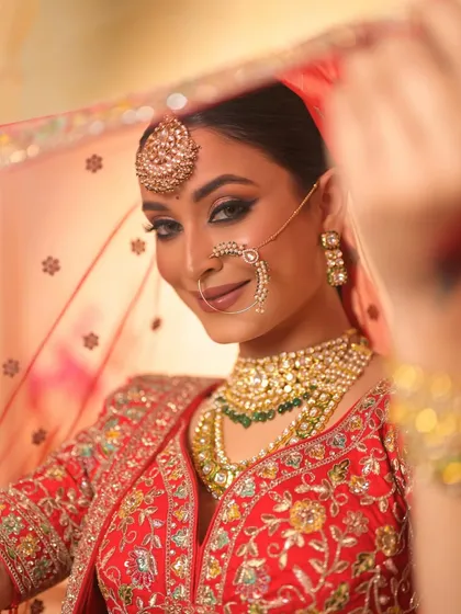 A playful peek from behind the dupatta. This shot is full of charm and highlights the bride's beautiful smile and sparkling eyes.