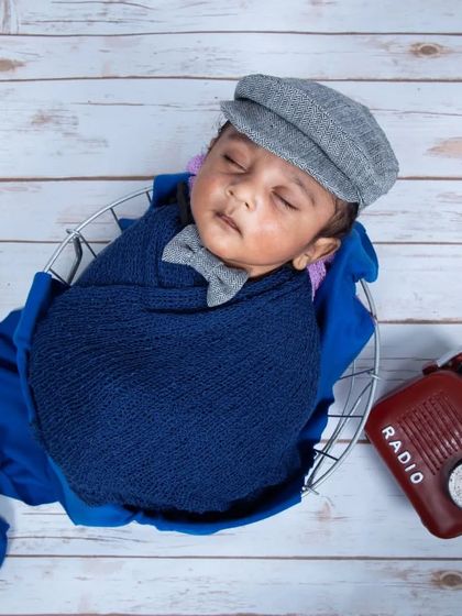 A timeless classic for a little gentleman. This vintage-inspired newborn setup with a newsboy cap and a retro radio prop creates a portrait that feels both charming and unique.