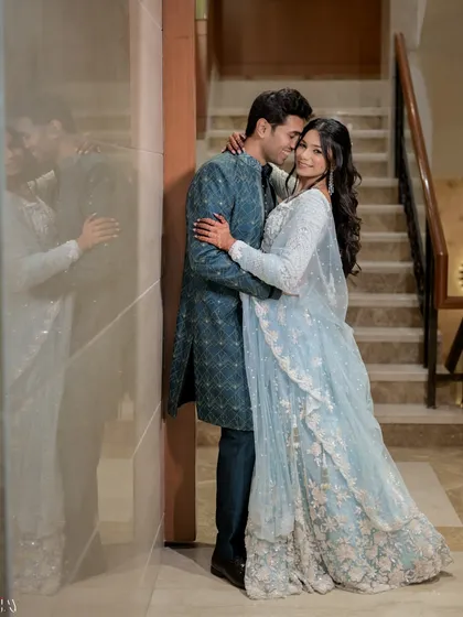 A beautiful portrait using a reflection to add an artistic element. The couple's embrace is mirrored in the glossy wall, creating a soft, dreamy effect that enhances the romance of the shot.