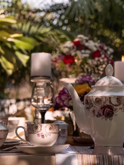 A Vigneto tea set captured during a golden hour garden party. The warm light and lush green background create a magical and inviting atmosphere for an evening tea.