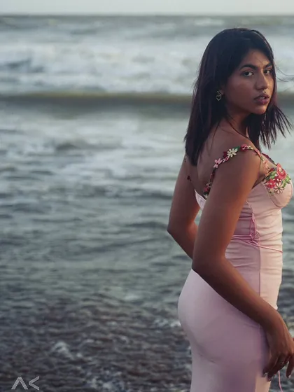A portrait taken during the soft light of dusk at the beach. The model's glance over her shoulder creates a candid, engaging moment.