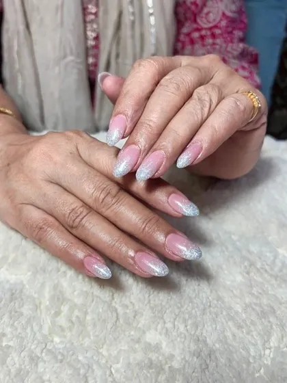A soft and elegant set of almond-shaped extensions with a pink base and a silver glitter fade from the tips.