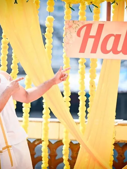 The groom is ready for his Haldi. This fun and casual shot captures the groom's excitement and the vibrant yellow decor of the ceremony.