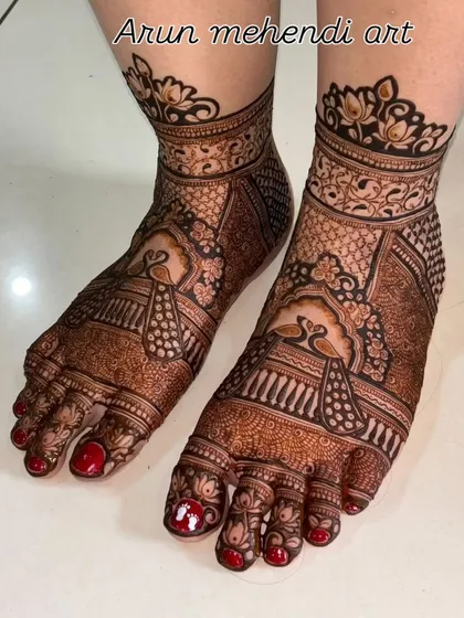 A close-up of intricate foot mehendi with detailed peacock figures. The use of negative space makes the design pop.