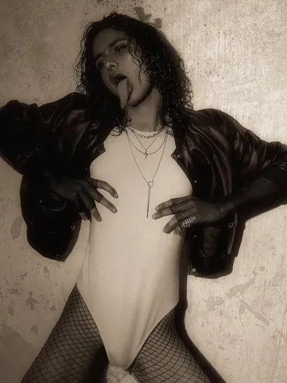A provocative and rebellious shot from a gothic-themed editorial. The pose and styling are designed to be confrontational and push boundaries.