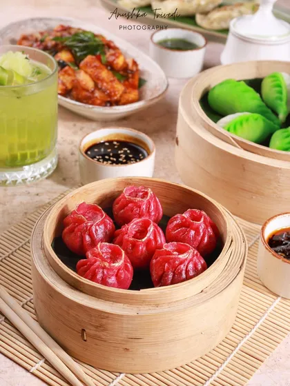 A wider shot of the dumpling spread, including green dumplings and other appetizers. This shows the variety of a restaurant's menu in a single, cohesive image.