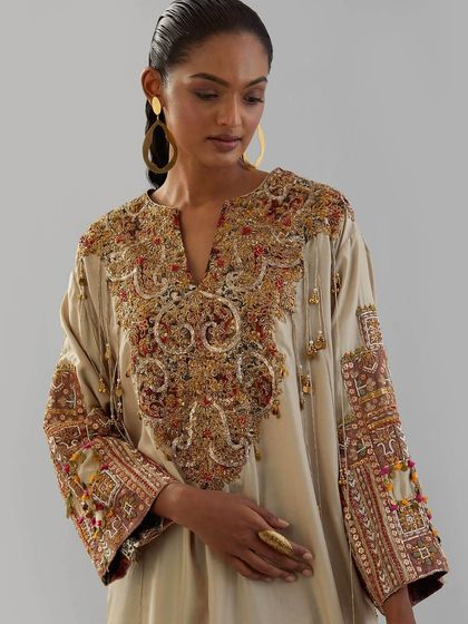 A close-up of a beige kurta with a heavily embroidered yoke, featuring a rich tapestry of colors and textures.