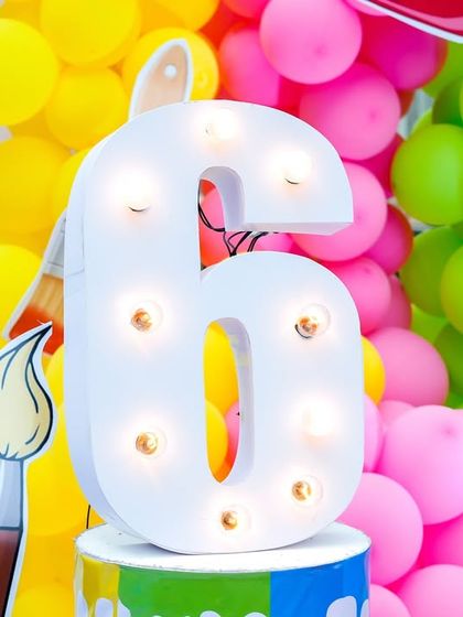 A close-up of the light-up number '6' and colorful balloon arrangement from the art party decor.