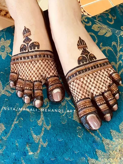 A detailed look at the foot mehandi created for an engagement. The design features elephant motifs and intricate net patterns, covering the feet and toes.