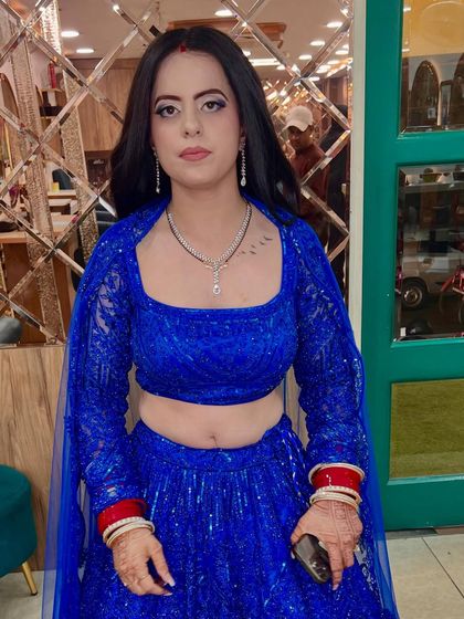 The final look, showing the client ready to go. The traditional red bangles add a beautiful contrast to the modern blue lehenga.