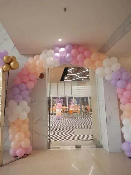 The entrance to Sia's butterfly party, featuring a pastel balloon arch and a welcome sign with a lit-up frame.