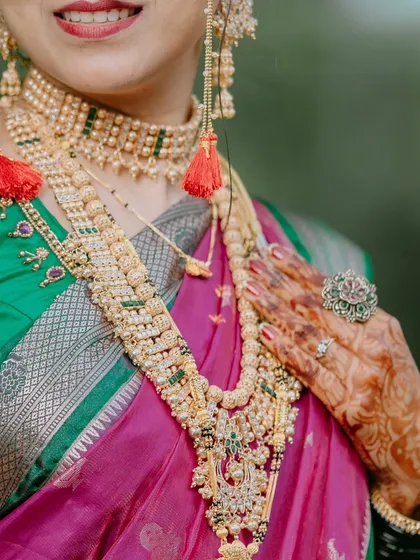 A detail shot focusing on the bride's stunning temple jewellery, intricate mehndi design, and the rich fabric of her saree.